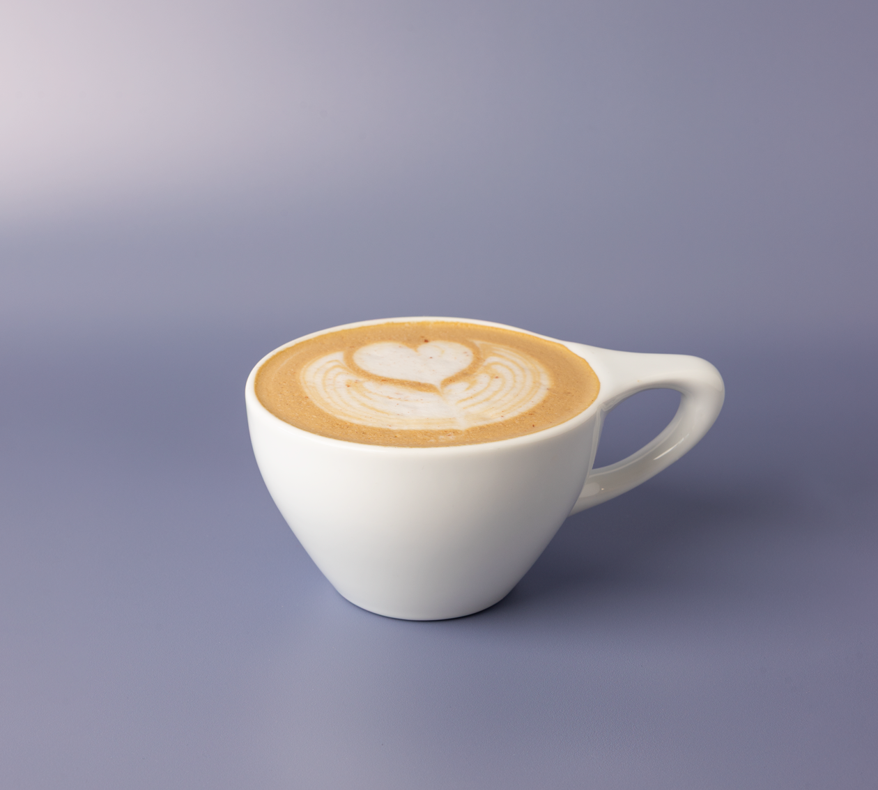 Pecan praline latte in a white ceramic cup with heart latte art and coarse pink salt scattered across the foam.