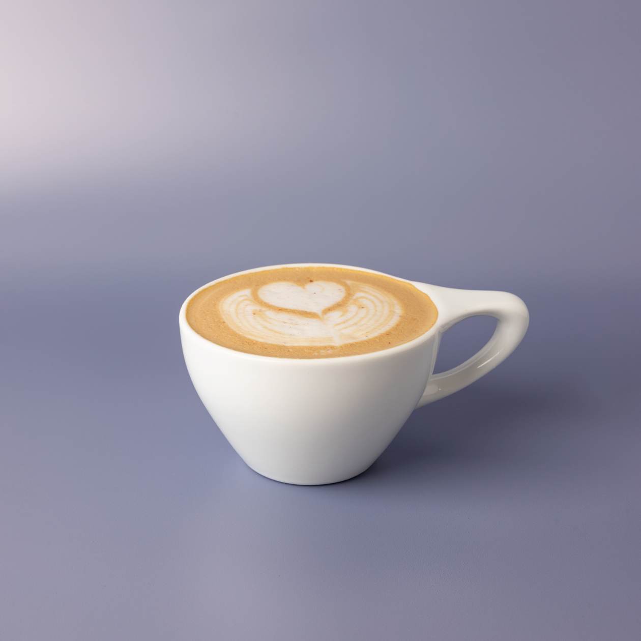Pecan praline latte in a white ceramic cup with heart latte art and coarse pink salt scattered across the foam.