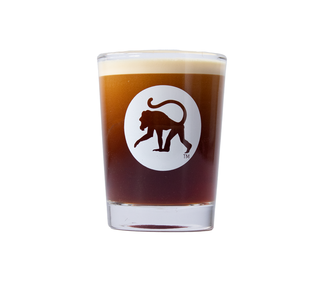 Frothy Monkey logo shot glass filled with espresso, white monkey emblem on clear thick-walled glass.