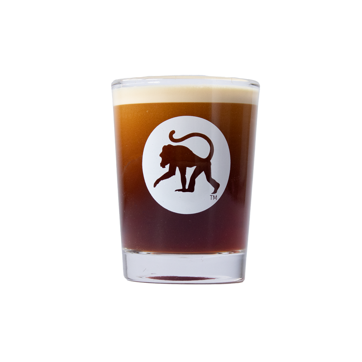 Frothy Monkey logo shot glass filled with espresso, white monkey emblem on clear thick-walled glass.