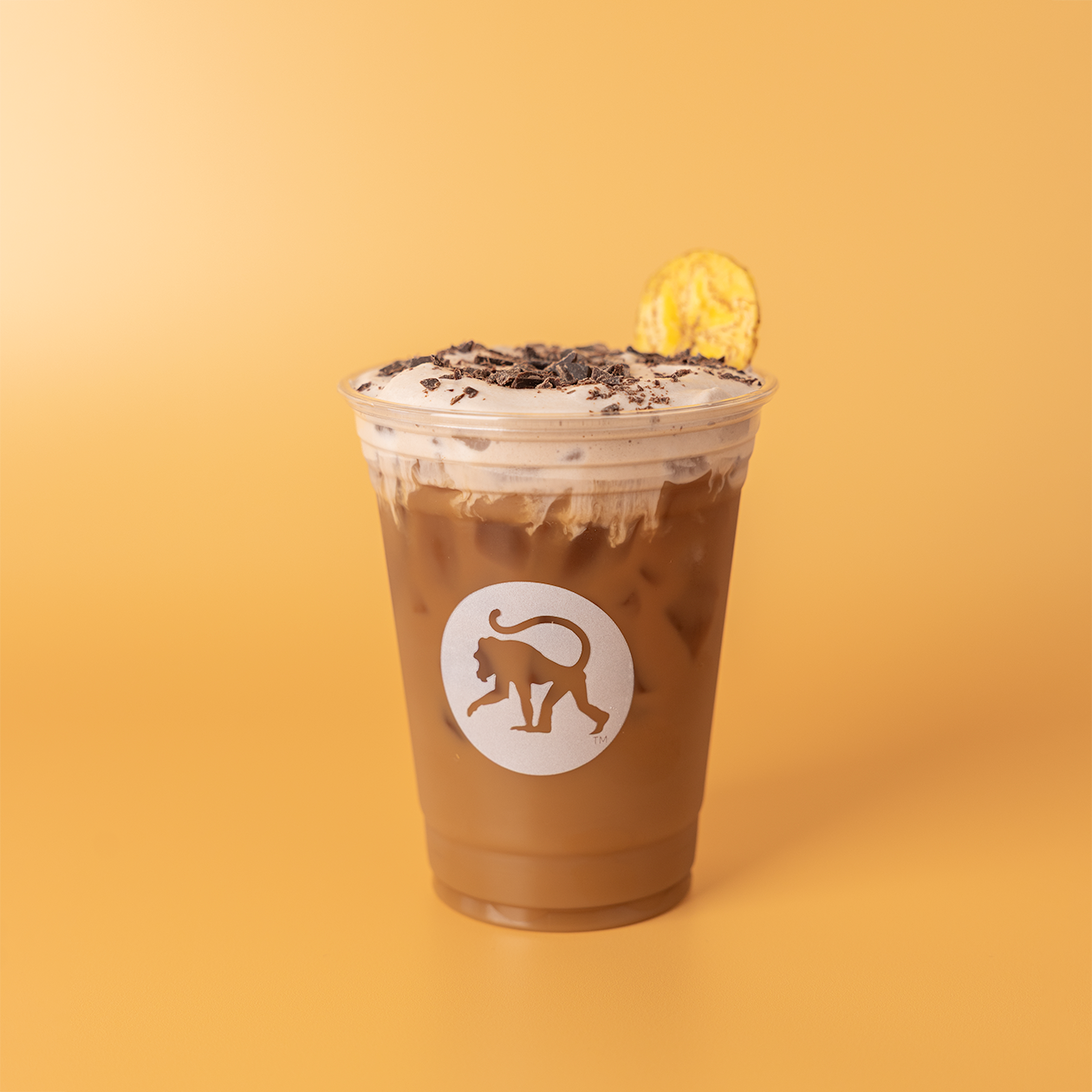 Chocolate banana bread cold brew in a Frothy Monkey branded cup, with cold foam, chocolate shavings, and a banana chip.