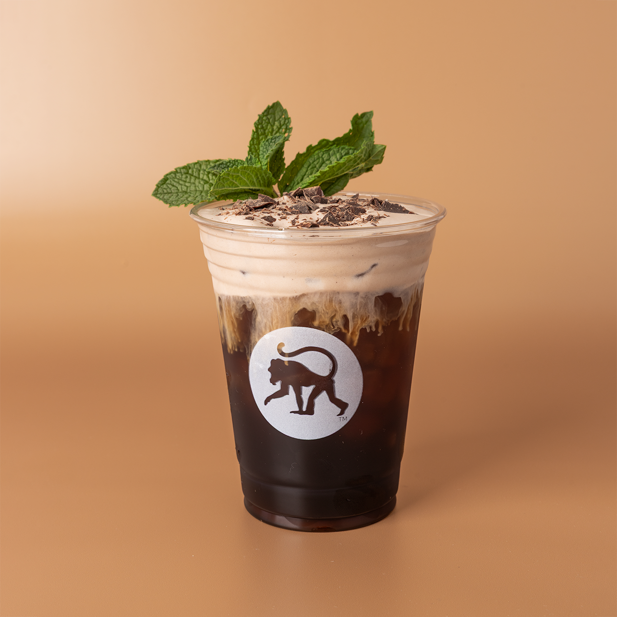 Chocolate mint cookie cold brew in a Frothy Monkey branded cup, topped with cold foam, cookie crumbles, and fresh mint.