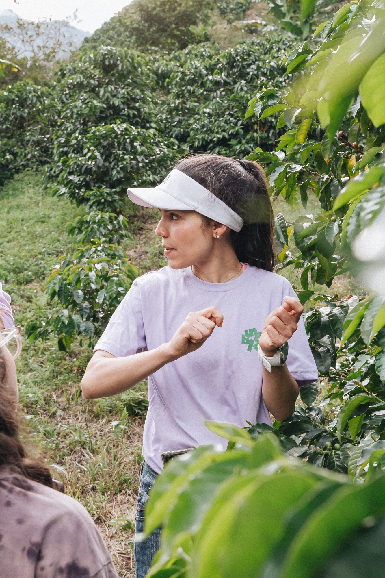 Carolina Ramirez talking with her hands raised mid-gesture in a coffee row at San Antonio farm, Andes, Antioquia, 1,850 MASL