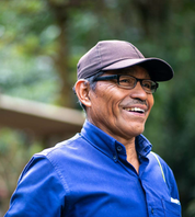 Smiling farm worker Ruperto Bernardina in blue button-down shirt and cap at Finca Santa Juana, Apaneca-Ilamatepec, El Salvador
