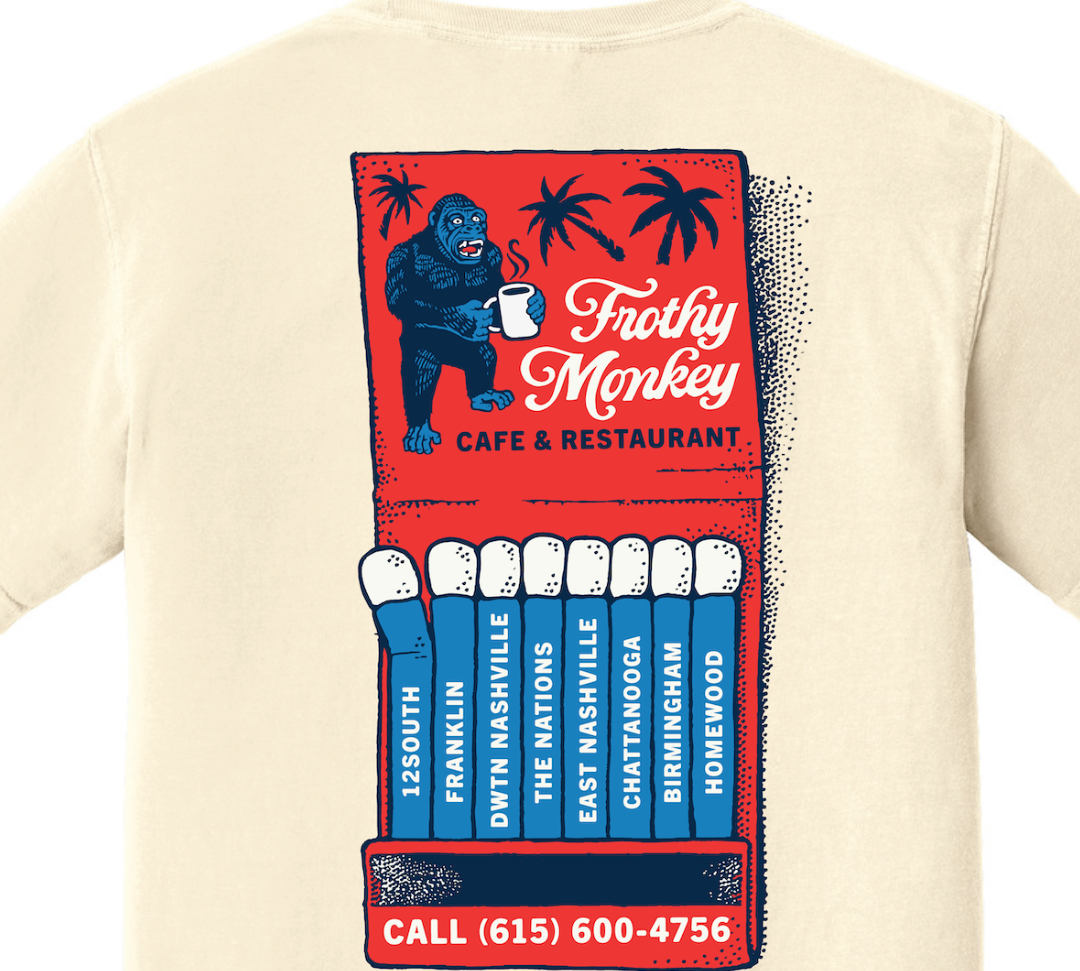 Back of the Frothy Monkey Matchbook tee in cream, close view of the hand-drawn red matchbook graphic with Kong the gorilla holding a steaming mug, palm trees, and the Frothy Monkey script logo above Cafe & Restaurant, with blue matches labeled 12South, Franklin, Dwtn Nashville, The Nations, East Nashville, Chattanooga, Birmingham, and Homewood, and Call (615) 600-4756 across the bottom, printed in red and navy on Comfort Colors 1717
