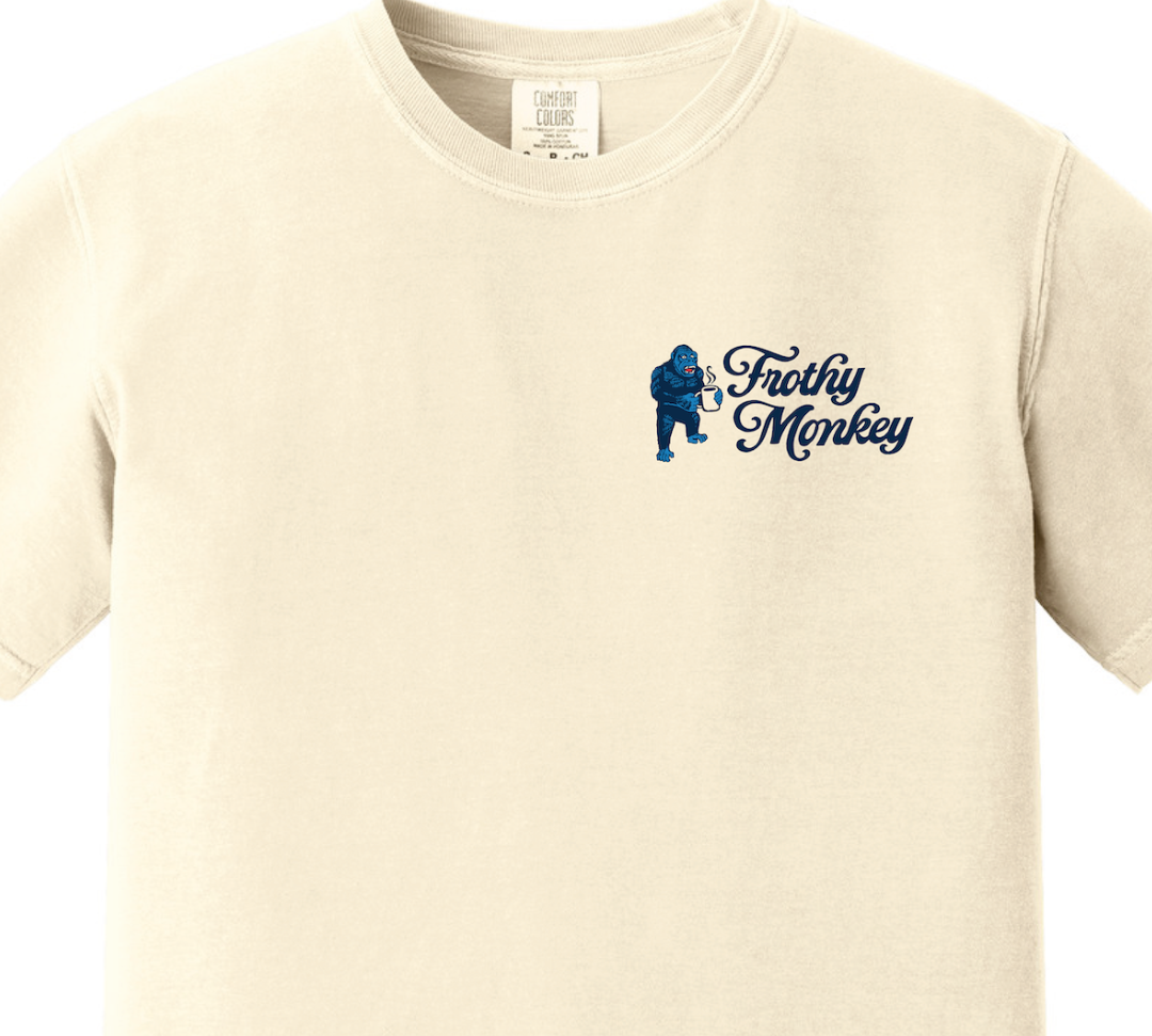 Front of the Frothy Monkey Matchbook tee in cream, close view of the navy left chest print showing Kong the gorilla holding a steaming coffee mug beside the Frothy Monkey script logo, on a garment dyed Comfort Colors 1717 short sleeve t-shirt