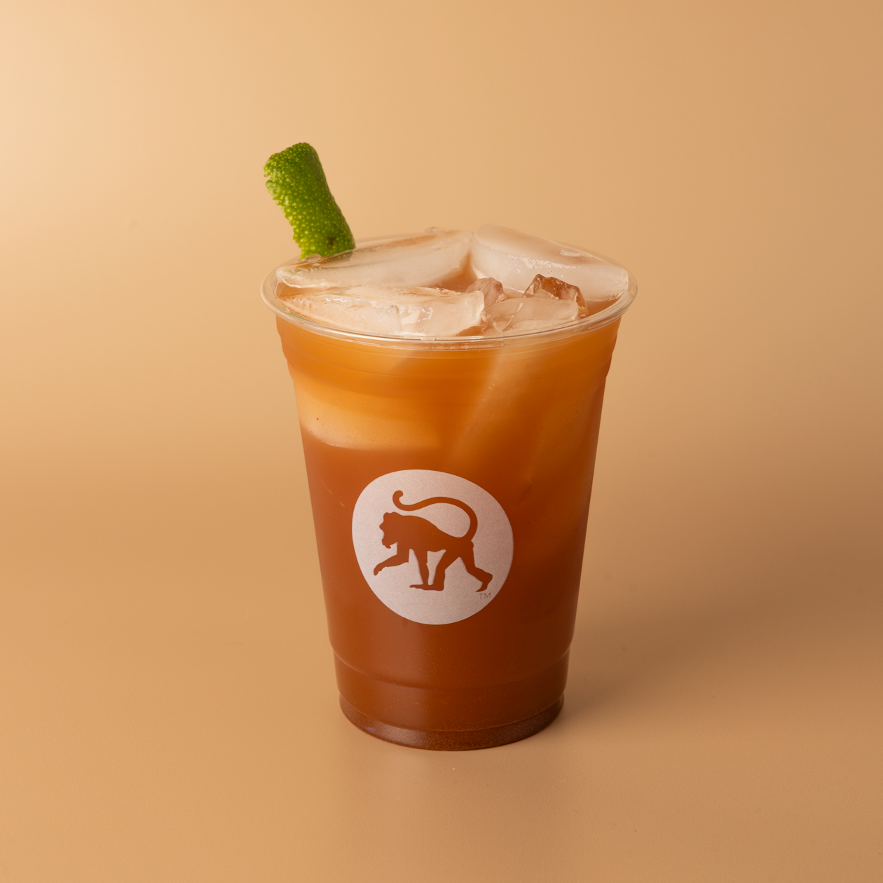 16oz Frothy Monkey branded cup of Ginger Chai Limeade with Firepot chai poured over ginger beer and a fresh lime peel garnish on top.