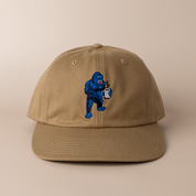 Frothy Monkey Kong dad hat in driftwood brown with Kong the gorilla holding a steaming coffee mug embroidered on the front crown in navy and blue thread, unstructured six-panel premium cotton cap with pre-curved visor