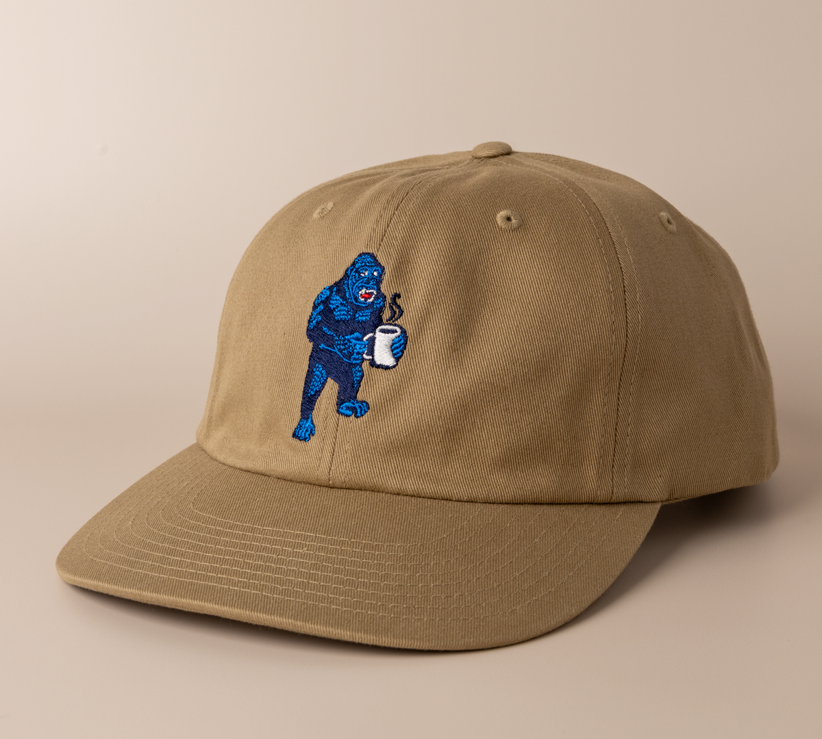 Driftwood brown Frothy Monkey Kong dad hat shown at a three-quarter angle, low-profile unstructured crown and pre-curved visor with the navy and blue Kong coffee embroidery on the front panel