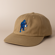 Driftwood brown Frothy Monkey Kong dad hat shown at a three-quarter angle, low-profile unstructured crown and pre-curved visor with the navy and blue Kong coffee embroidery on the front panel