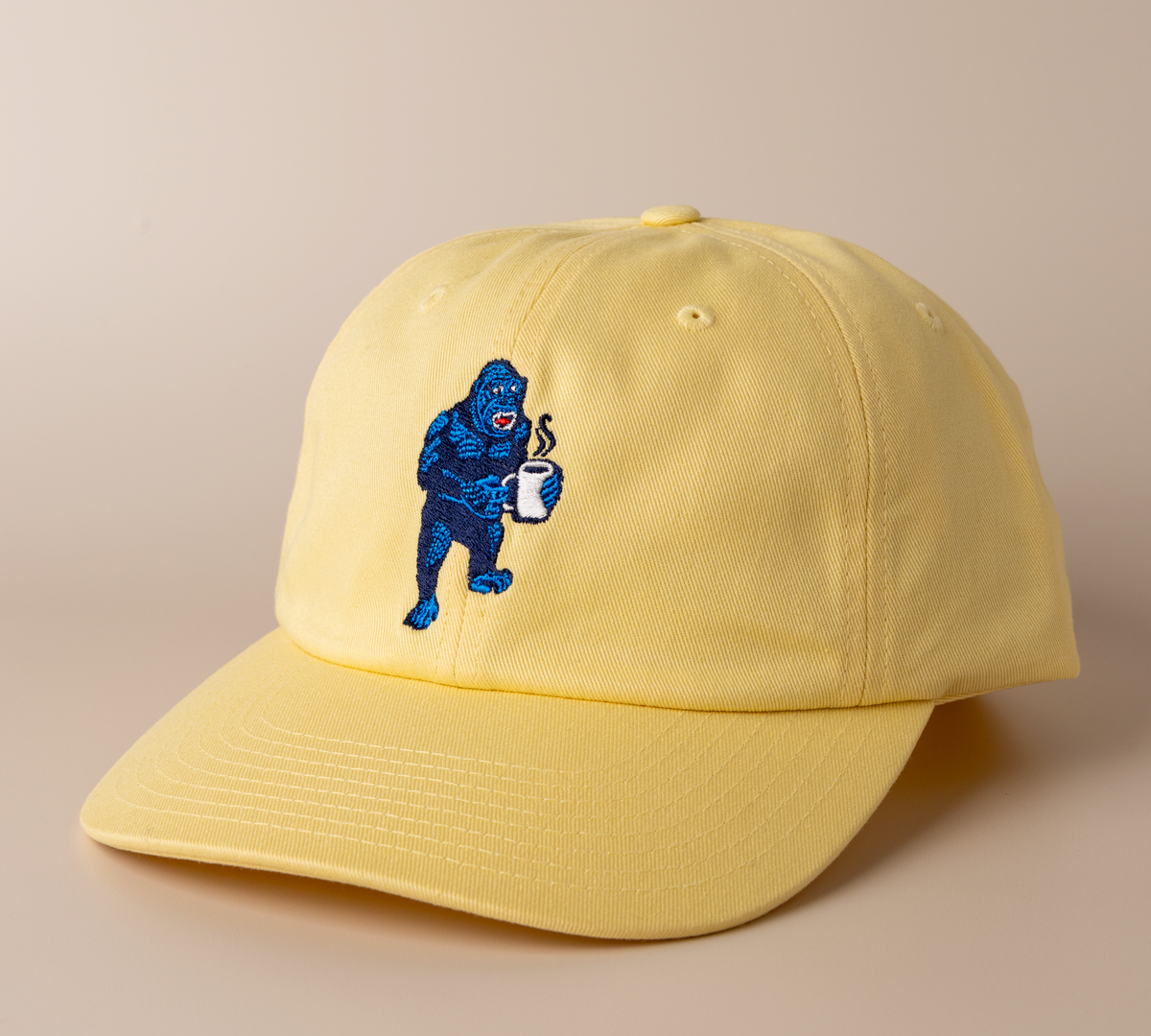 Banana yellow Frothy Monkey Kong dad hat shown at a three-quarter angle, low-profile unstructured crown and pre-curved visor with the navy and blue Kong coffee embroidery on the front panel