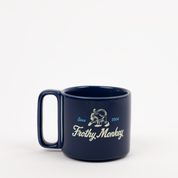 Single Frothy Monkey 10 oz stackable ceramic mug in Navy Blue with vintage logo in cream and Howler Blue accents, side view