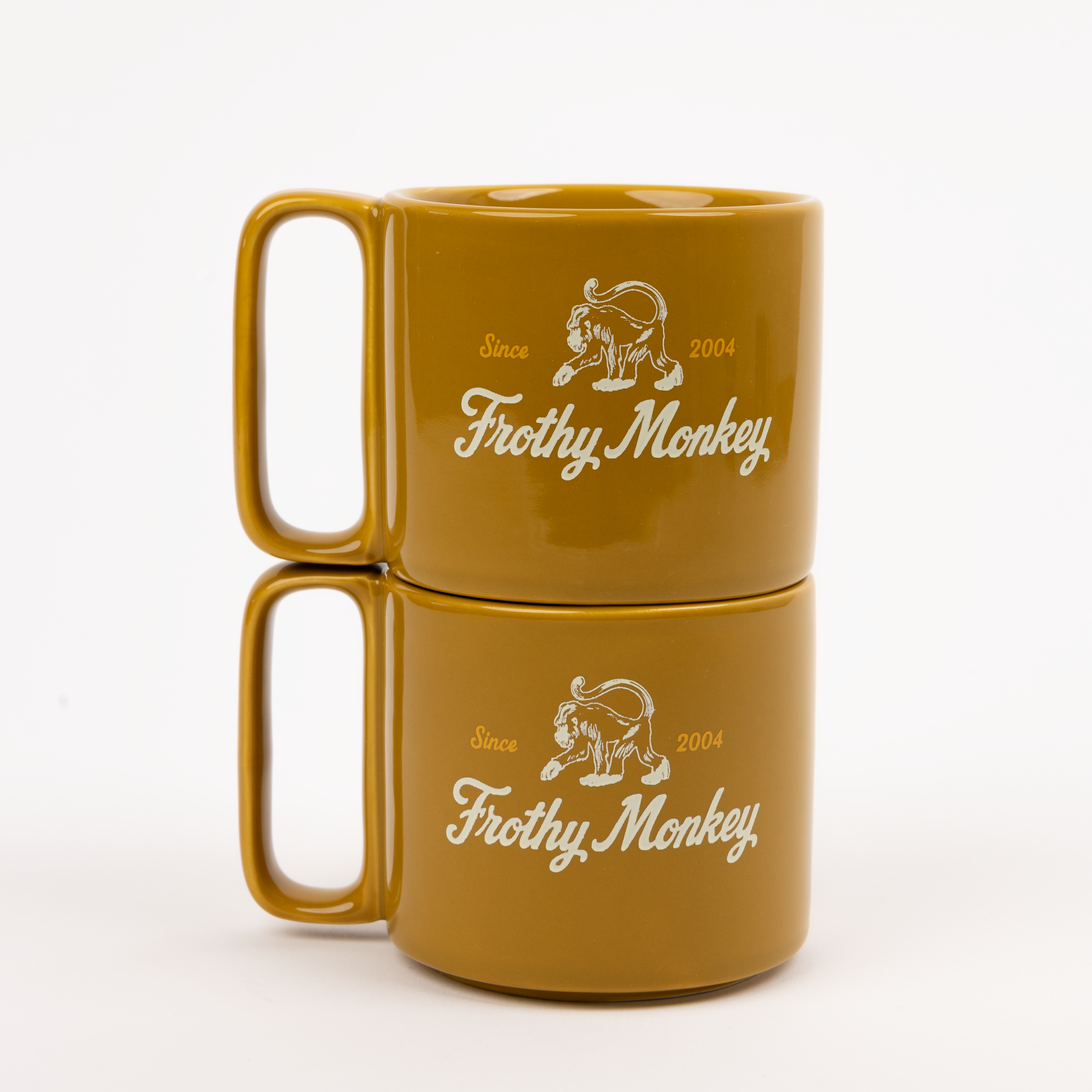 Two Frothy Monkey 10 oz stackable ceramic mugs in Chai stacked on top of each other, showing vintage Since 2004 monkey logo in cream with Brunch Yellow accents