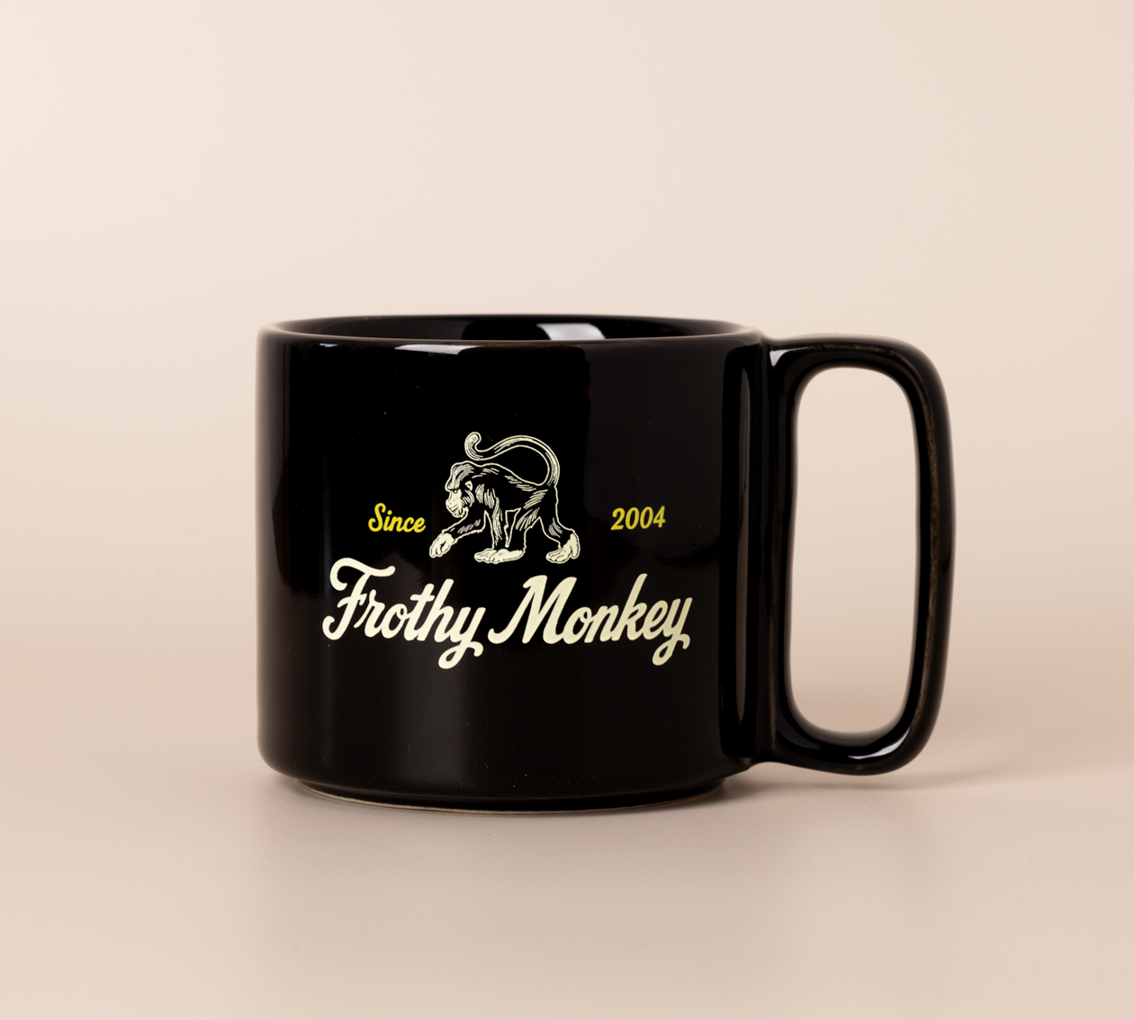 Single Frothy Monkey 10 oz stackable ceramic mug in Black with vintage logo in cream and yellow accents, side view