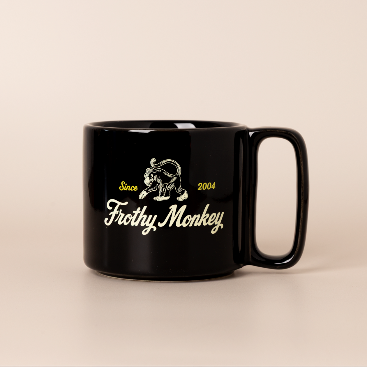 Single Frothy Monkey 10 oz stackable ceramic mug in Black with vintage logo in cream and yellow accents, side view