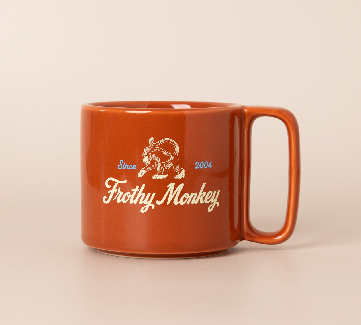 Single Frothy Monkey 10 oz stackable ceramic mug in burnt orange with vintage logo in cream and Howler Blue accents, side view