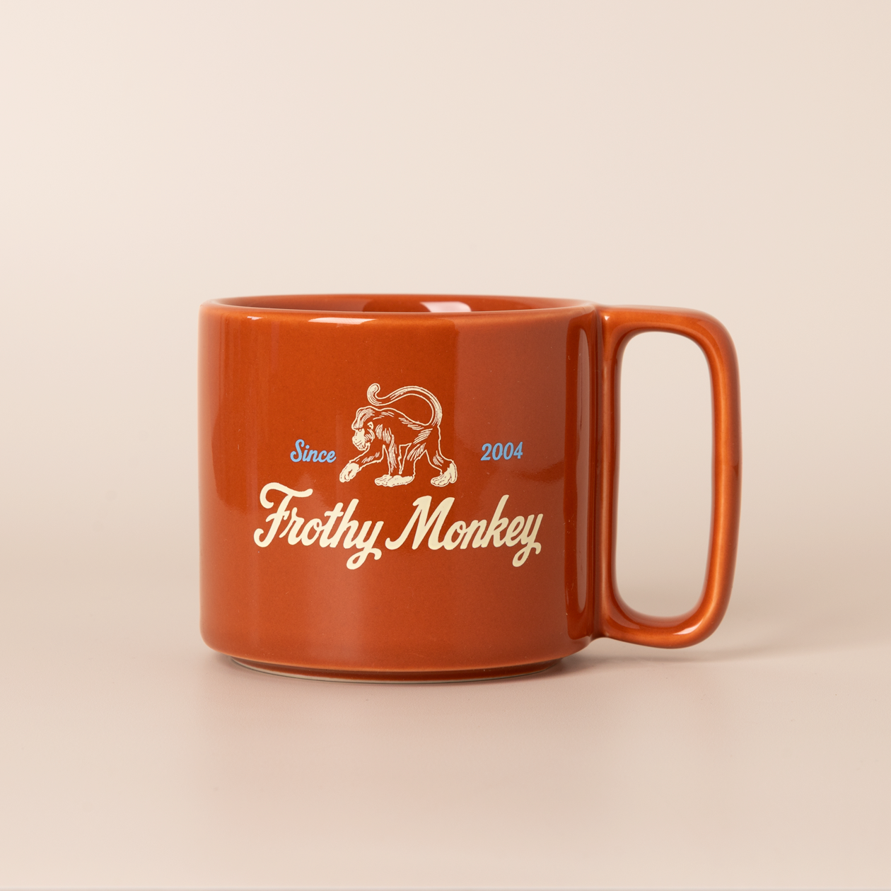 Single Frothy Monkey 10 oz stackable ceramic mug in burnt orange with vintage logo in cream and Howler Blue accents, side view