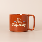 Single Frothy Monkey 10 oz stackable ceramic mug in burnt orange with vintage logo in cream and Howler Blue accents, side view