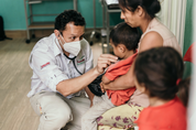 Doctor with a stethoscope examining a young child held by a woman at a health clinic, Guatemala